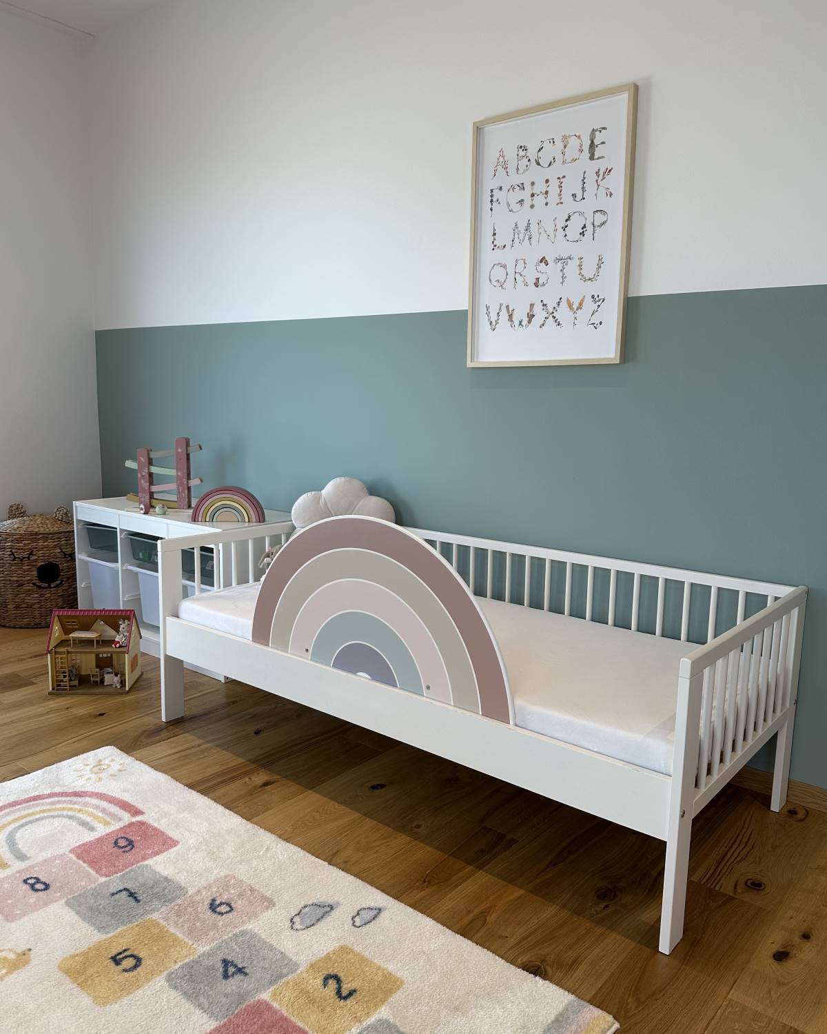 Regenbogen Rausfallschutz im hellen Kinderbett – dezente Sicherheit, die zum Zimmer passt.